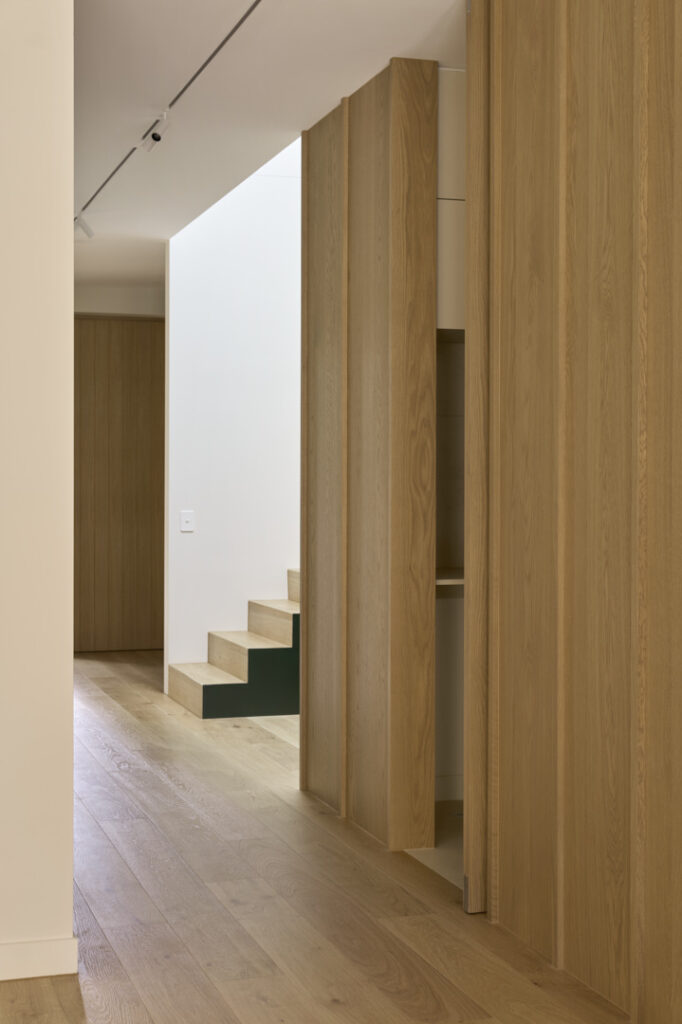 Oak-lined hallway with concealed doors in Fitzroy Passivhaus.