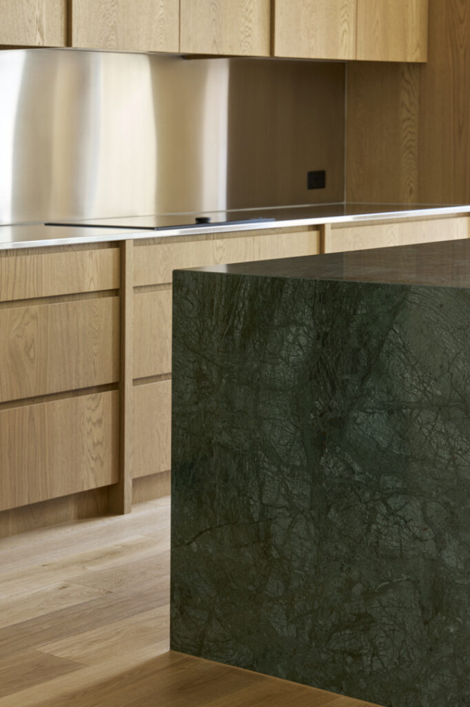 Detail of stone island bench and oak cabinetry in Fitzroy Passivhaus kitchen.