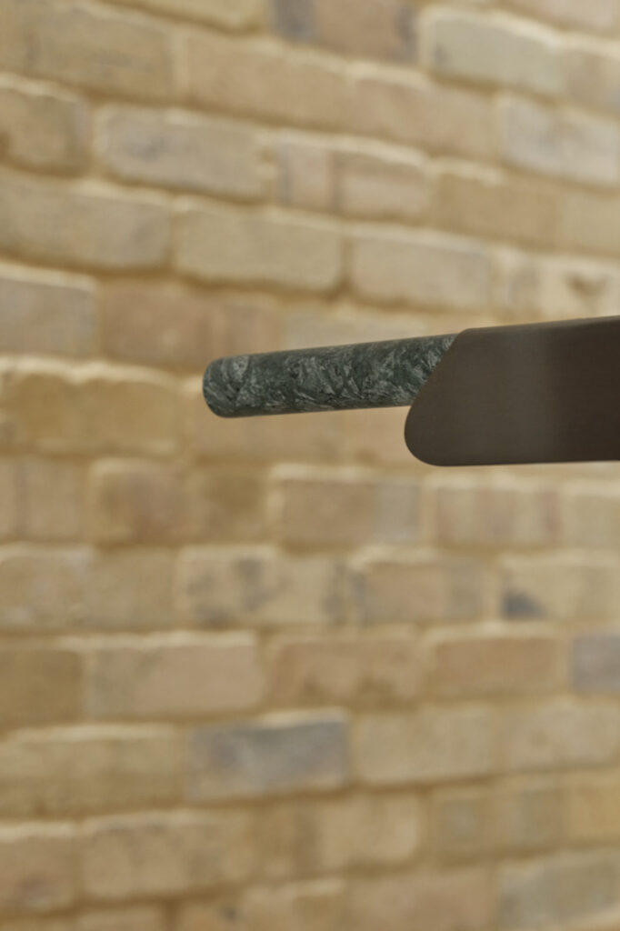 Pendant light suspended in front of textured internal brick feature wall.