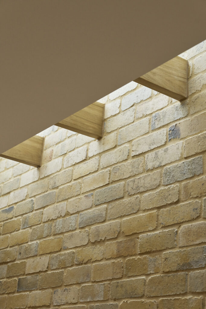 Strip skylight introducing natural daylight onto reused internal brick wall in Fitzroy Passivhaus extension.