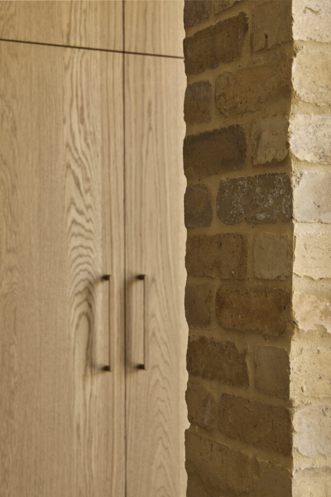 Detail of custom oak joinery integrated with reused internal brickwork wall in Fitzroy Passivhaus home.