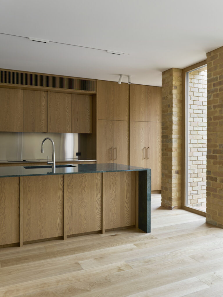 Oak kitchen cabinetry and island with full-height glazing in Fitzroy Passivhaus.