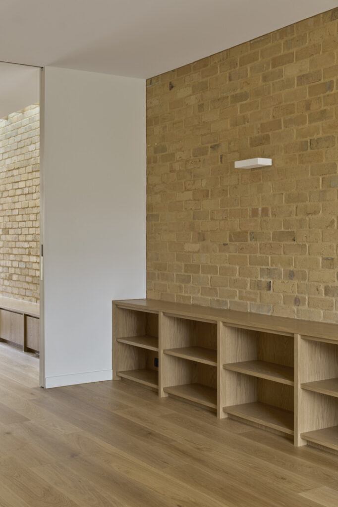 Low oak storage joinery set against internal brick feature wall.