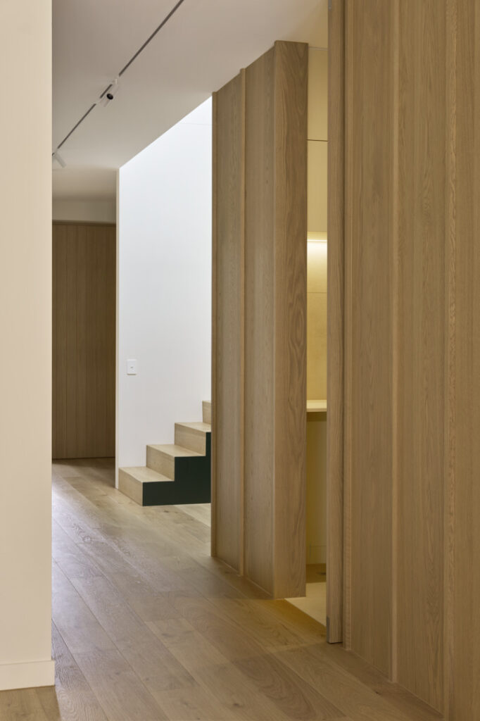 Full-height oak wall panelling concealing internal doors.